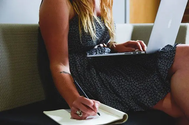 woman on laptop writing in notepad